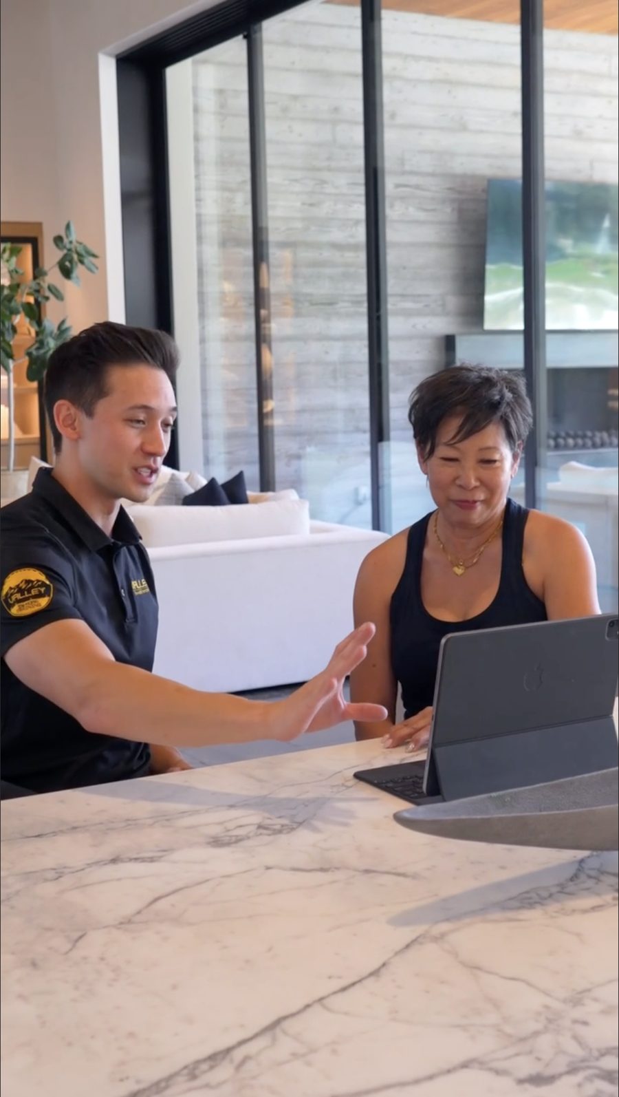 Trainer walking a client through her program on a tablet at the kitchen island