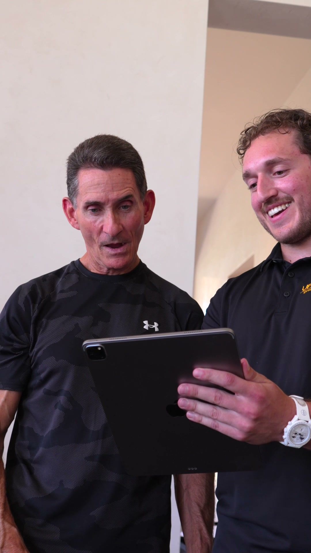 Trainer and client smiling while reviewing progress on a tablet
