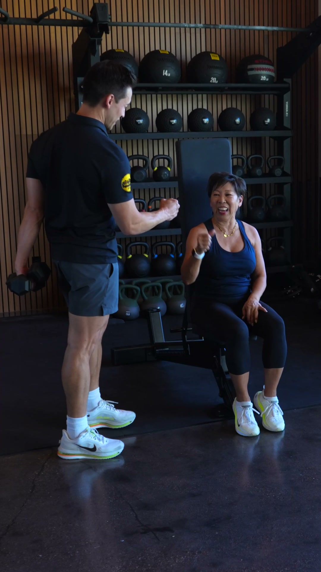 Trainer coaching a seated press in a home gym